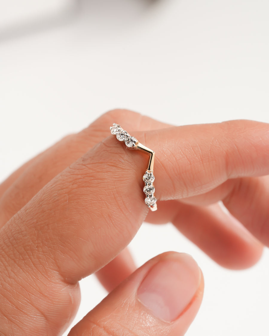 Chevron lab grown diamond wedding band in yellow gold held on a fingertip, V shaped with round stones