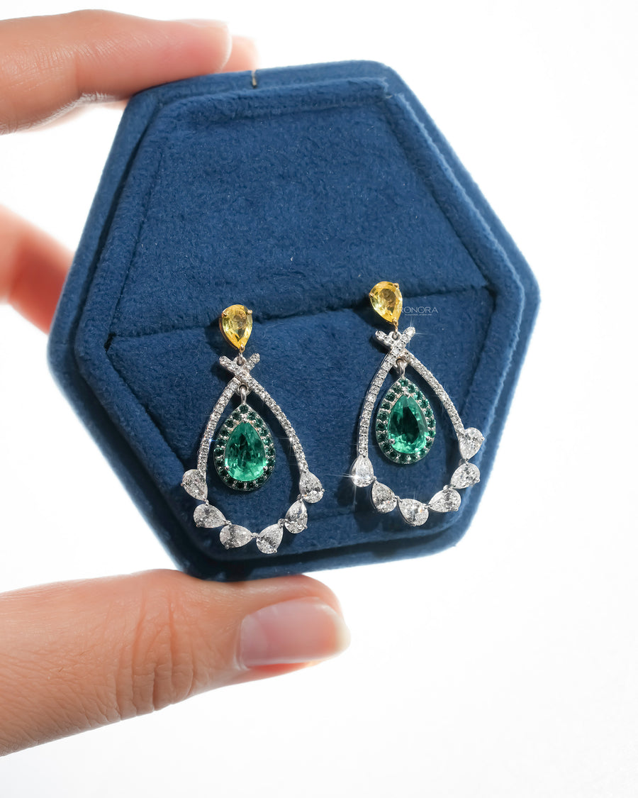 Pair of lab grown emerald pear drop earrings with yellow pear tops in a blue velvet hexagon jewelry box