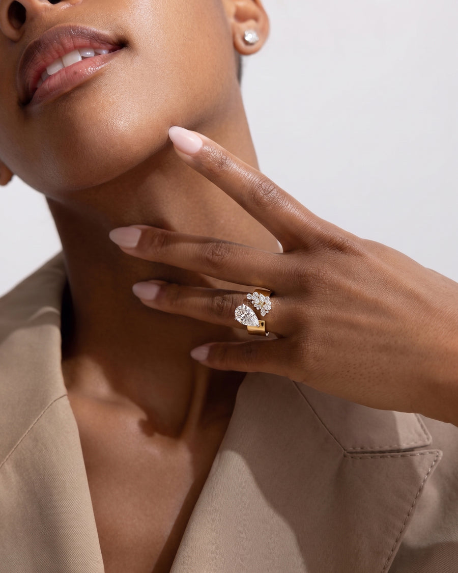 Model wearing a pear toi et moi lab grown diamond ring in yellow gold on her finger, hand resting at her chin