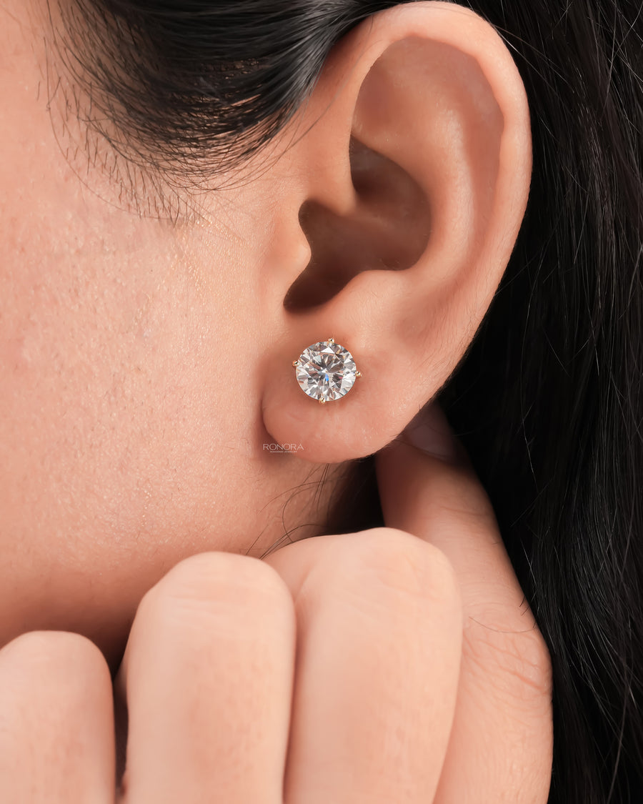 Close-up of a round lab grown diamond stud earring in a four prong gold setting worn on the ear