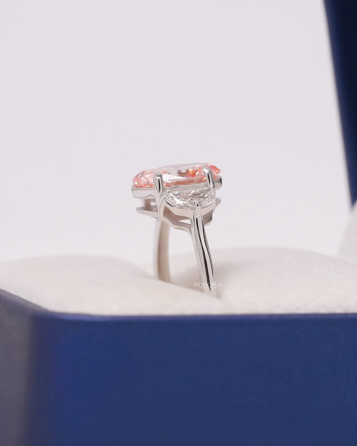 Side profile of pink lab grown diamond three-stone ring showing side-stone setting