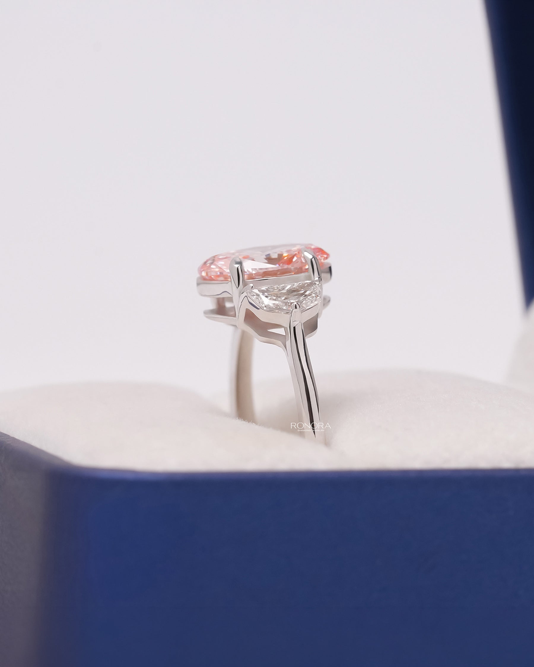 Side profile of pink lab grown diamond three-stone ring showing side-stone setting