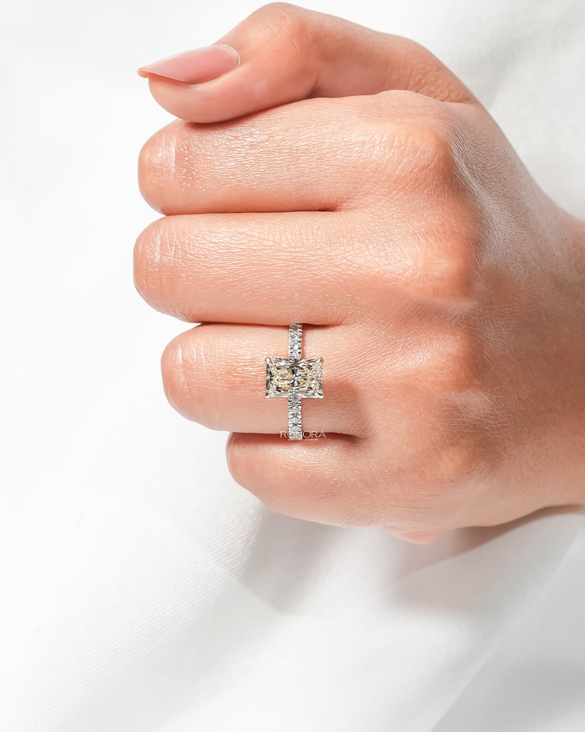 Radiant lab grown diamond pavé ring worn on hand in yellow gold