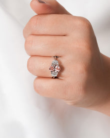 Pink lab grown diamond three-stone ring worn on hand in white metal