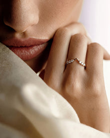 Model wearing a chevron lab grown diamond wedding band, hand resting at her chin against a cream cloth