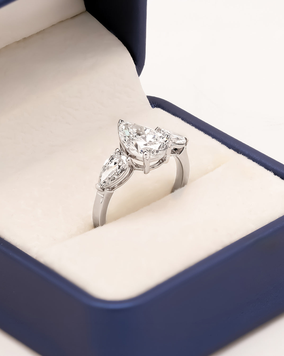 Angled view of pear lab grown diamond three-stone ring showing three-stone setting