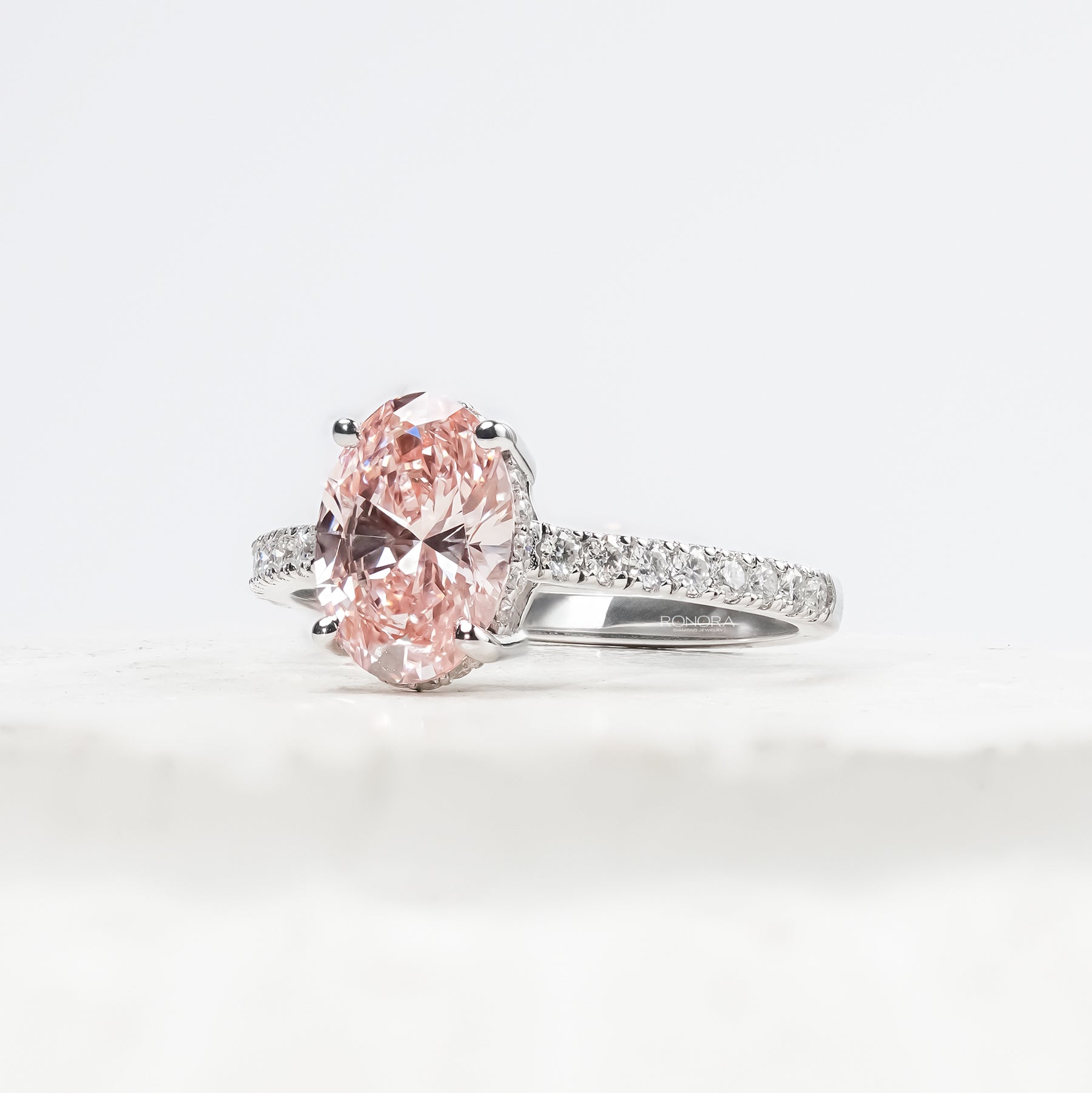 Angled view of pink oval lab grown diamond halo ring with halo pave setting