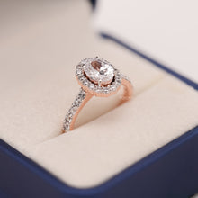 oval moissanite halo ring worn on hand in rose gold