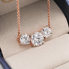 Three stone round lab grown diamond necklace in rose gold with graduated stones, resting in a grey jewelry box