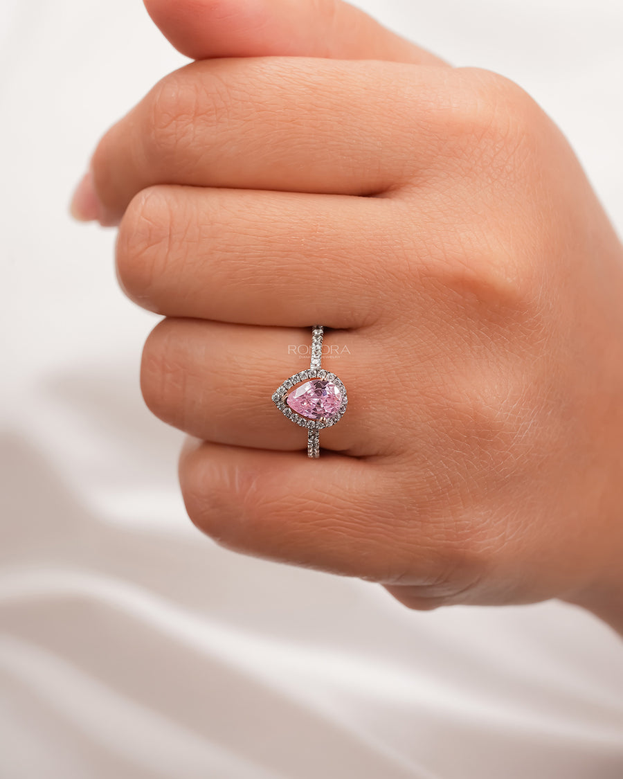 pink pear moissanite halo ring worn on hand in rose gold