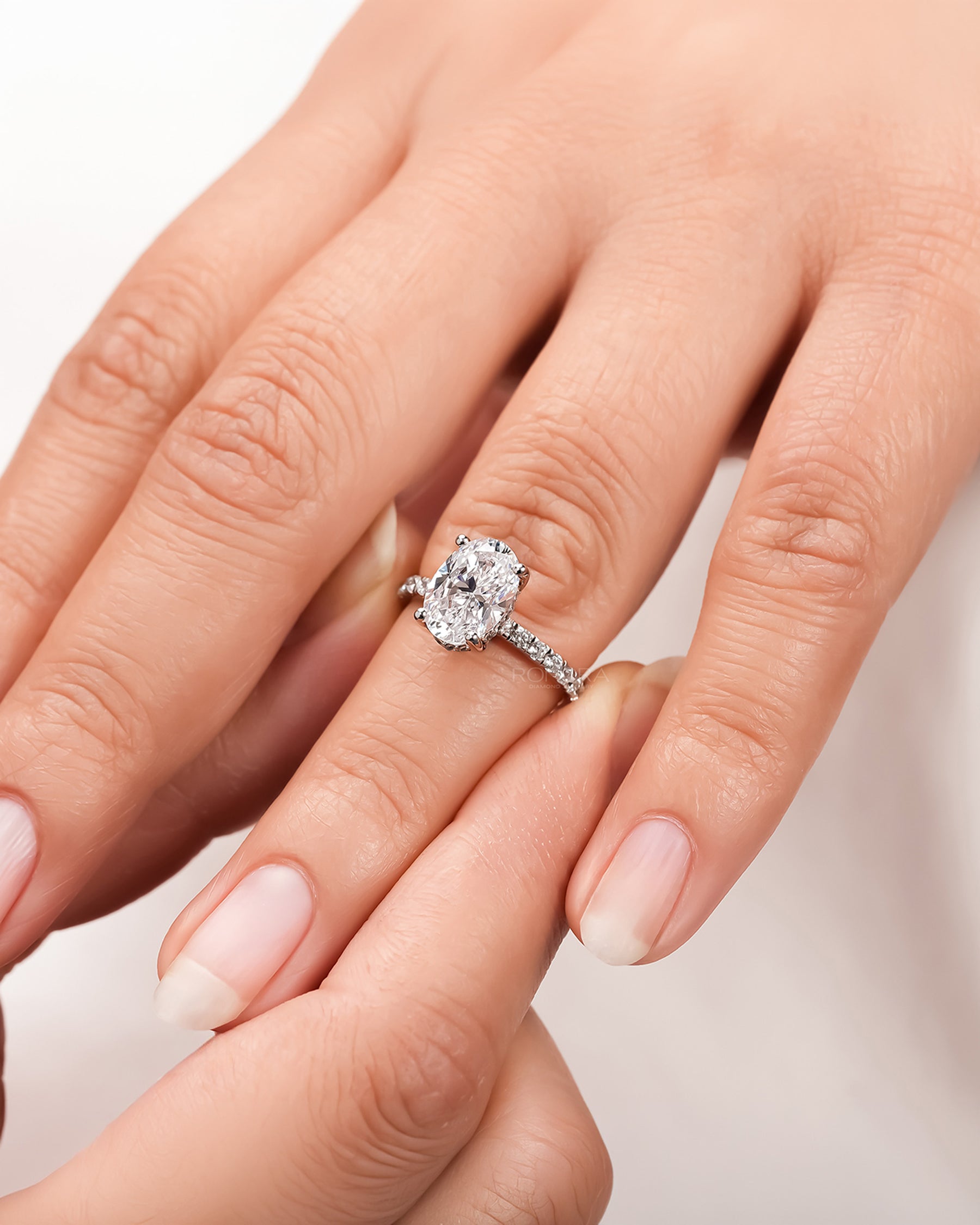 oval moissanite pave ring worn on hand in rose gold