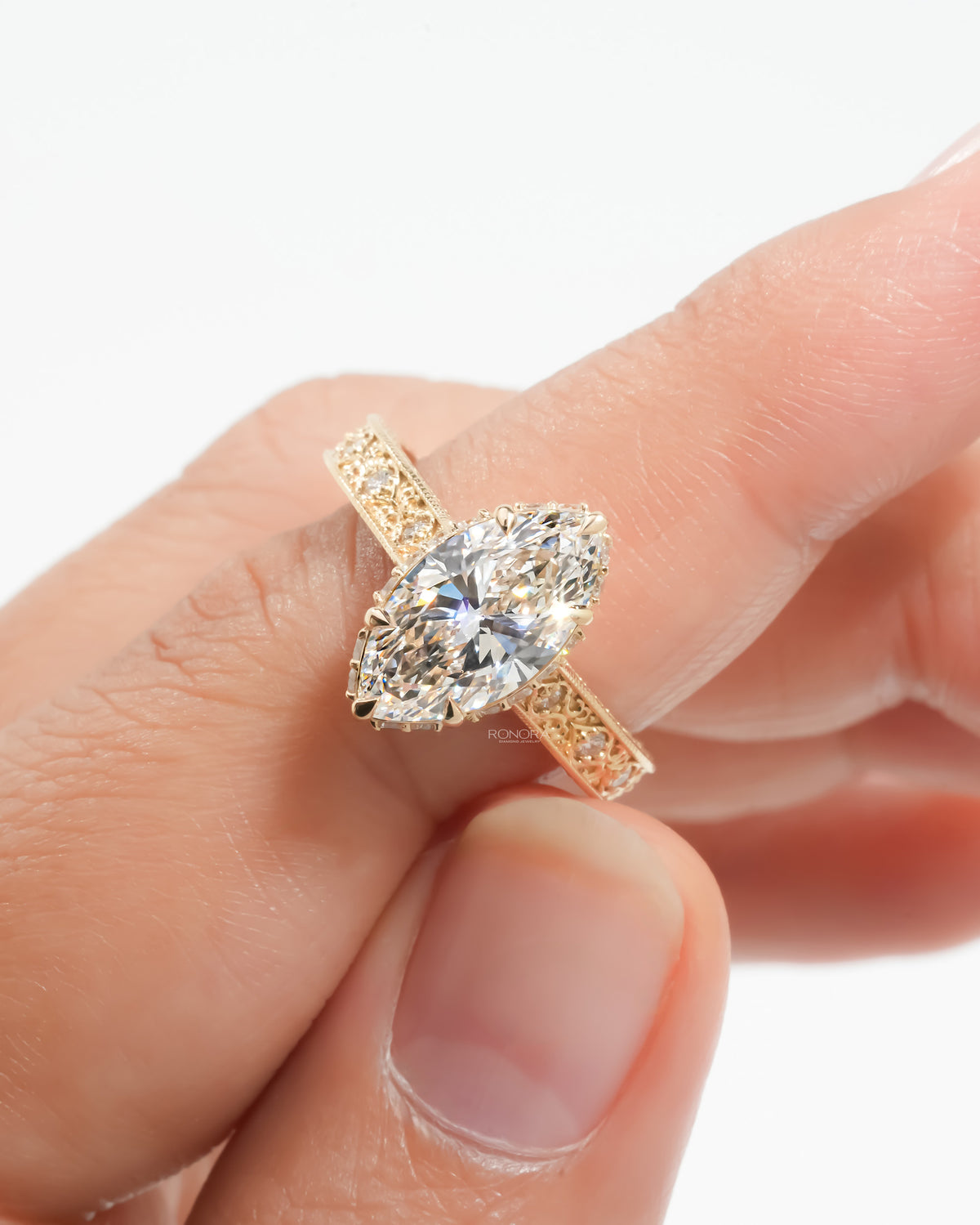 Vintage marquise lab grown diamond ring held between fingers showing the pave band
