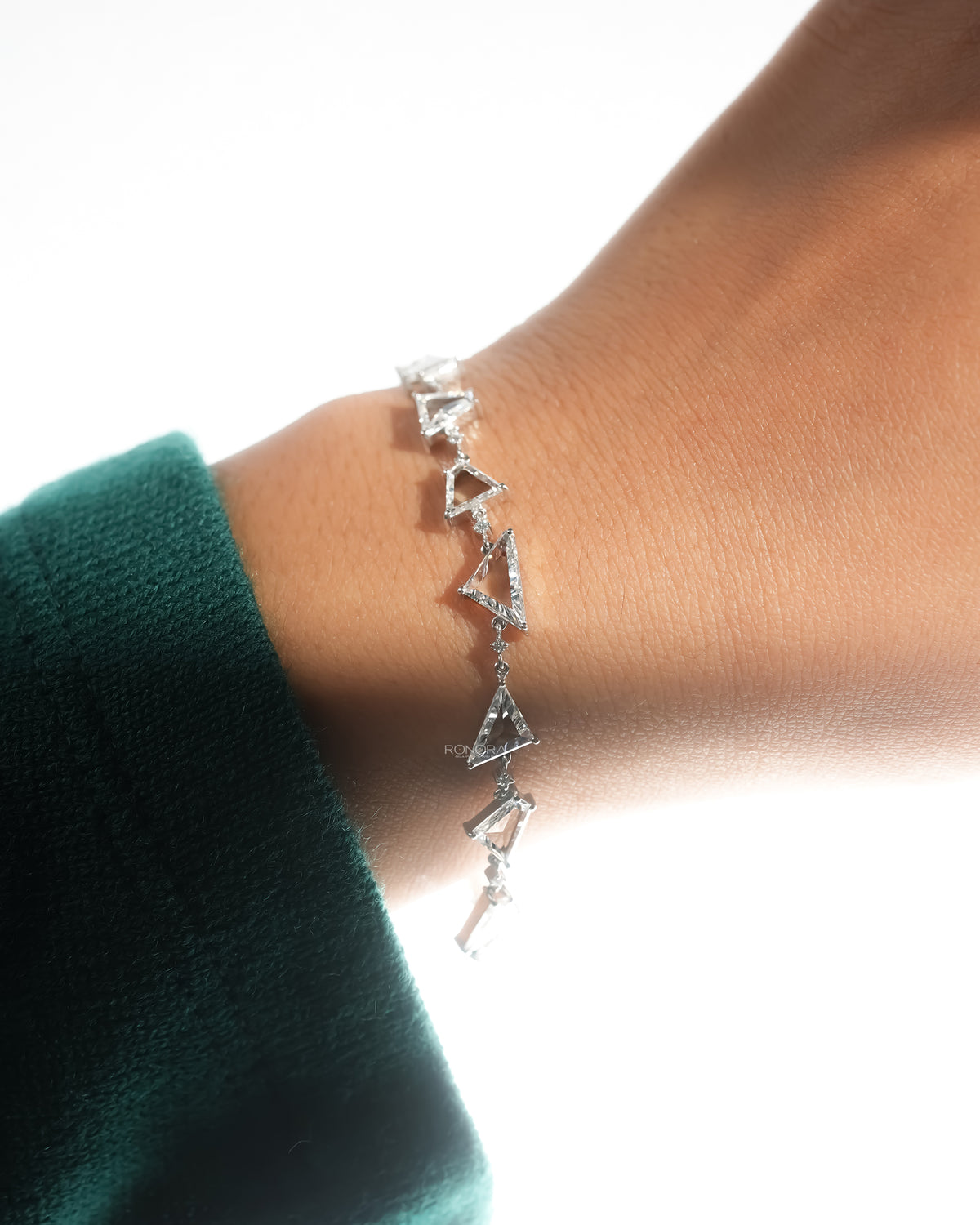 Multi shape lab grown diamond bracelet worn on the wrist with a green sleeve