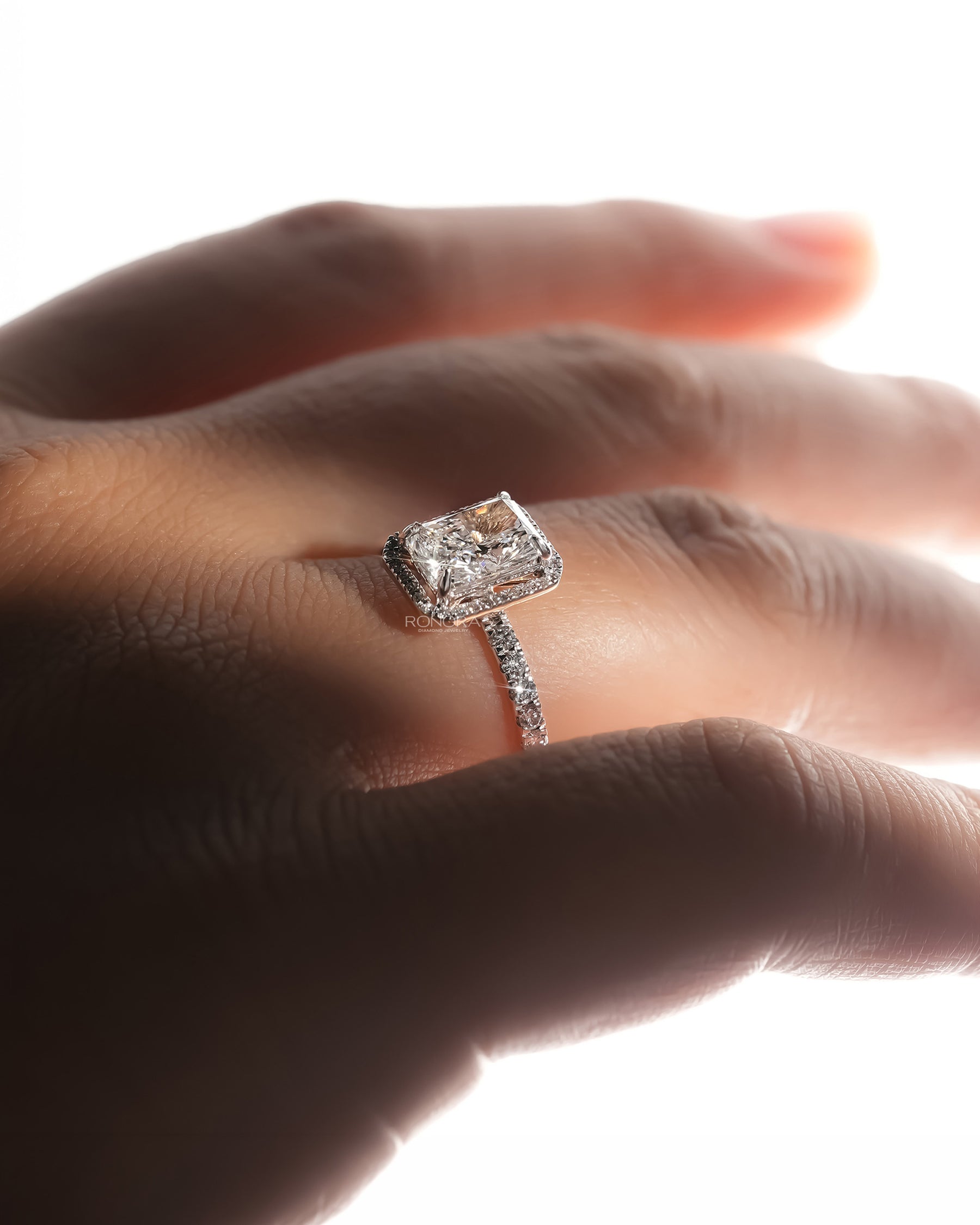 radiant lab grown diamond halo ring worn with luxury styling in white gold