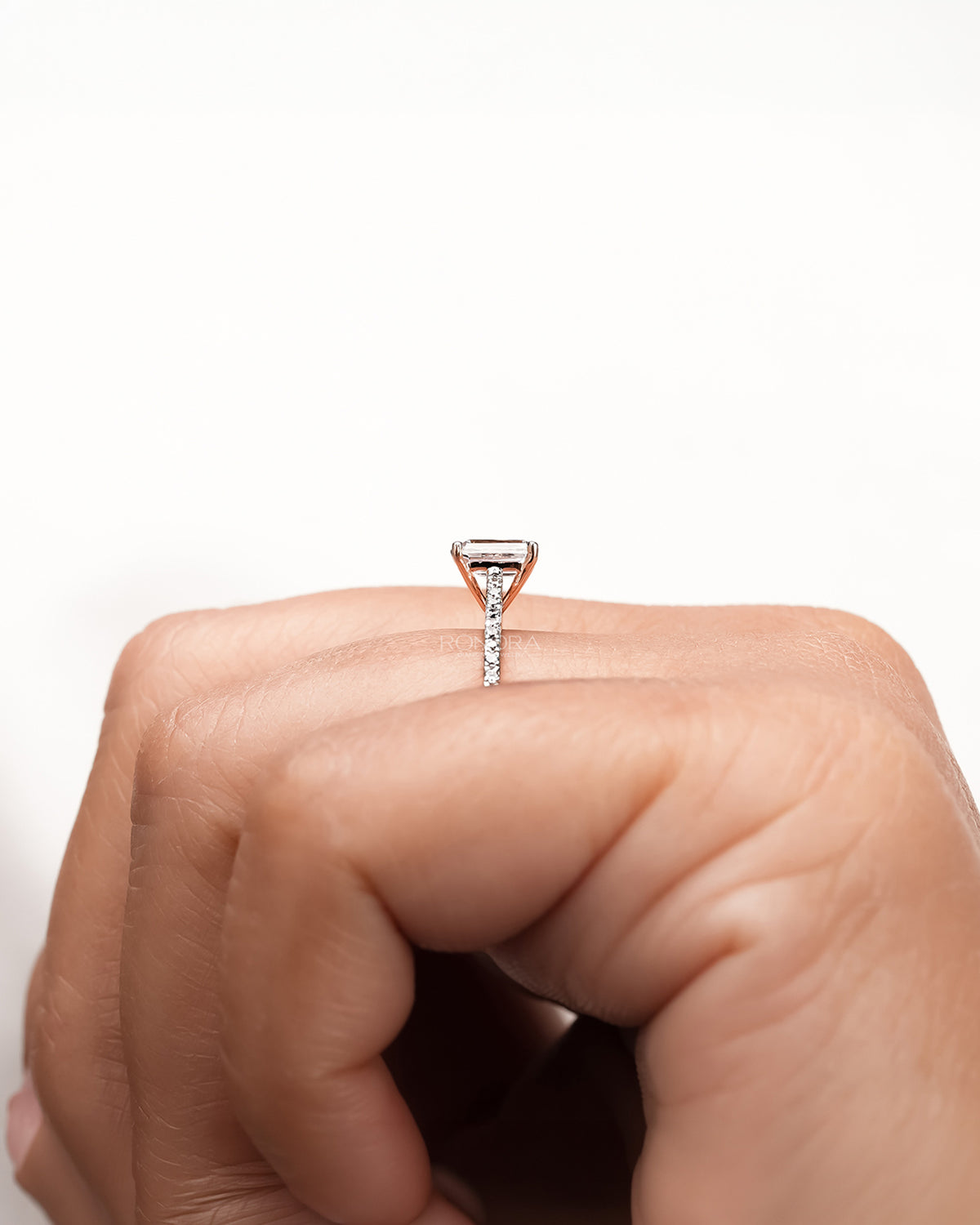 Angled view of emerald cut moissanite pave ring with pave setting