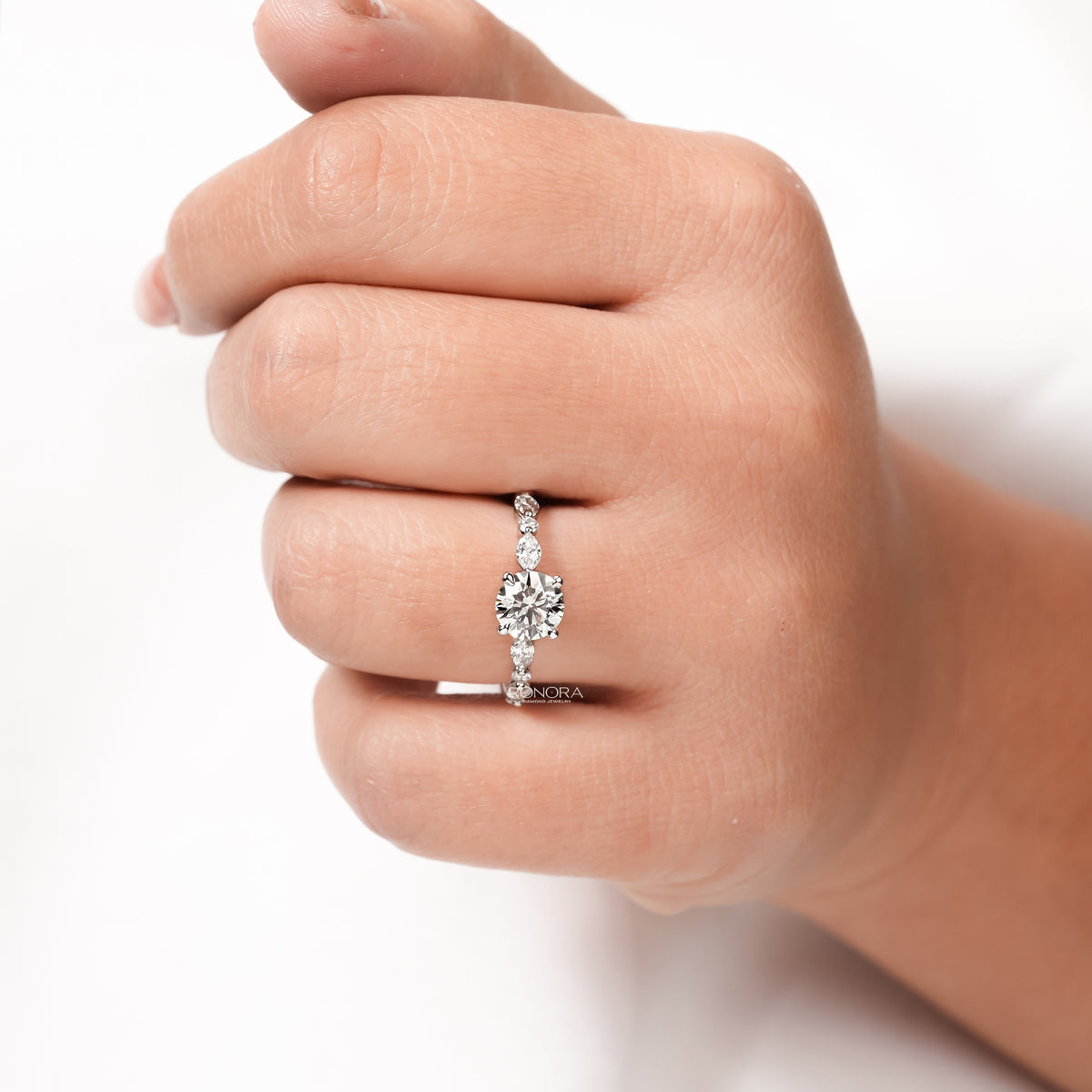round lab grown diamond side-stone ring worn on hand in white gold