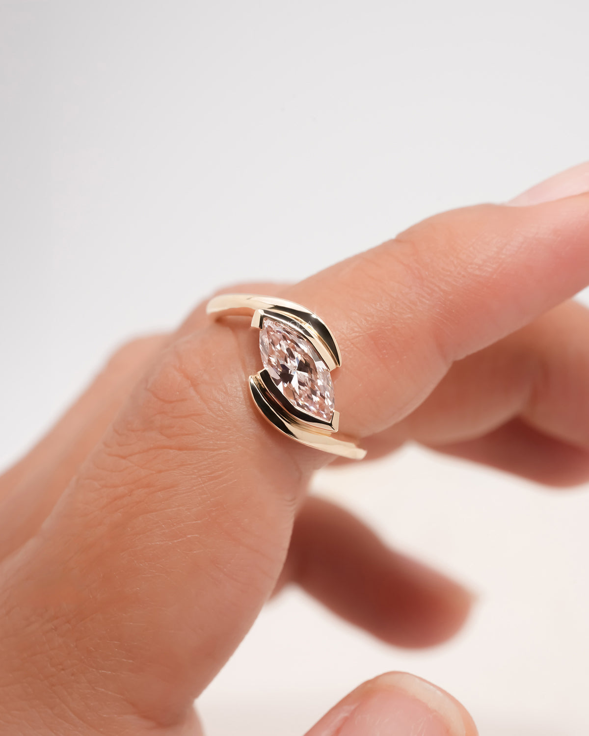 pink marquise lab grown diamond twist ring on hand with refined rose gold finish