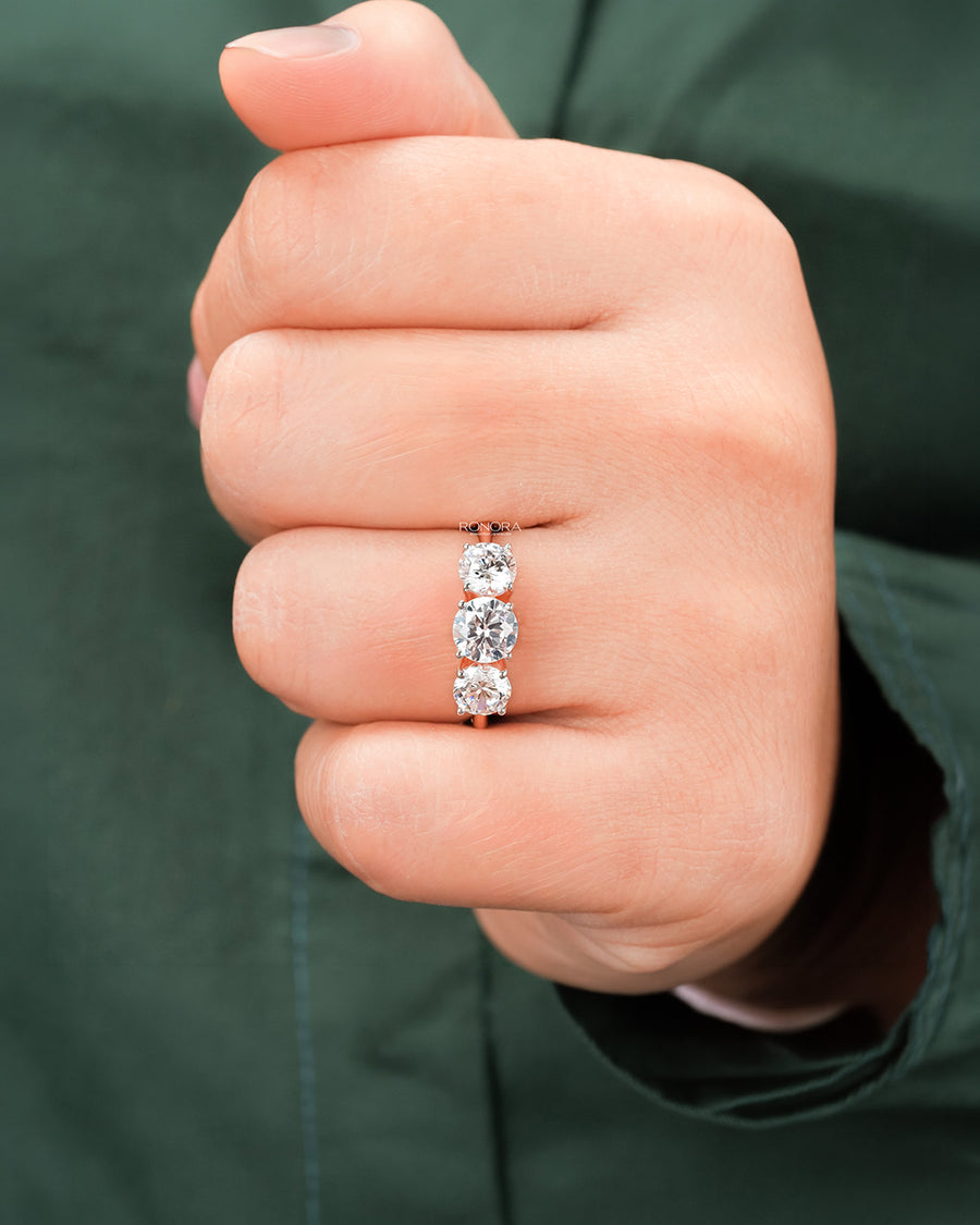 round lab grown diamond three-stone ring worn on hand in rose gold