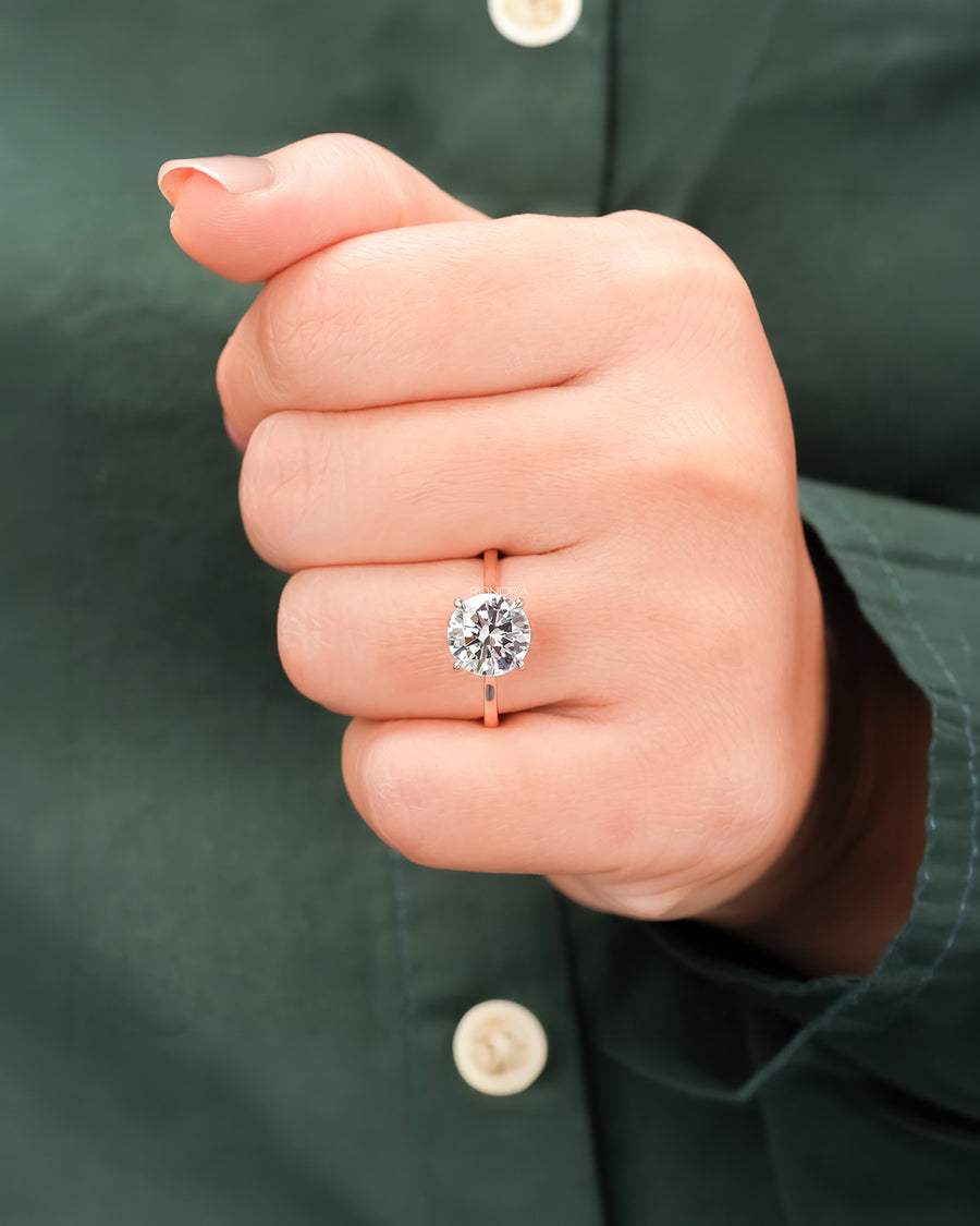 Round moissanite solitaire ring worn on hand in rose gold
