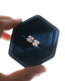 Cushion cut lab grown diamond earrings with double prongs in a navy velvet hex box held in hand