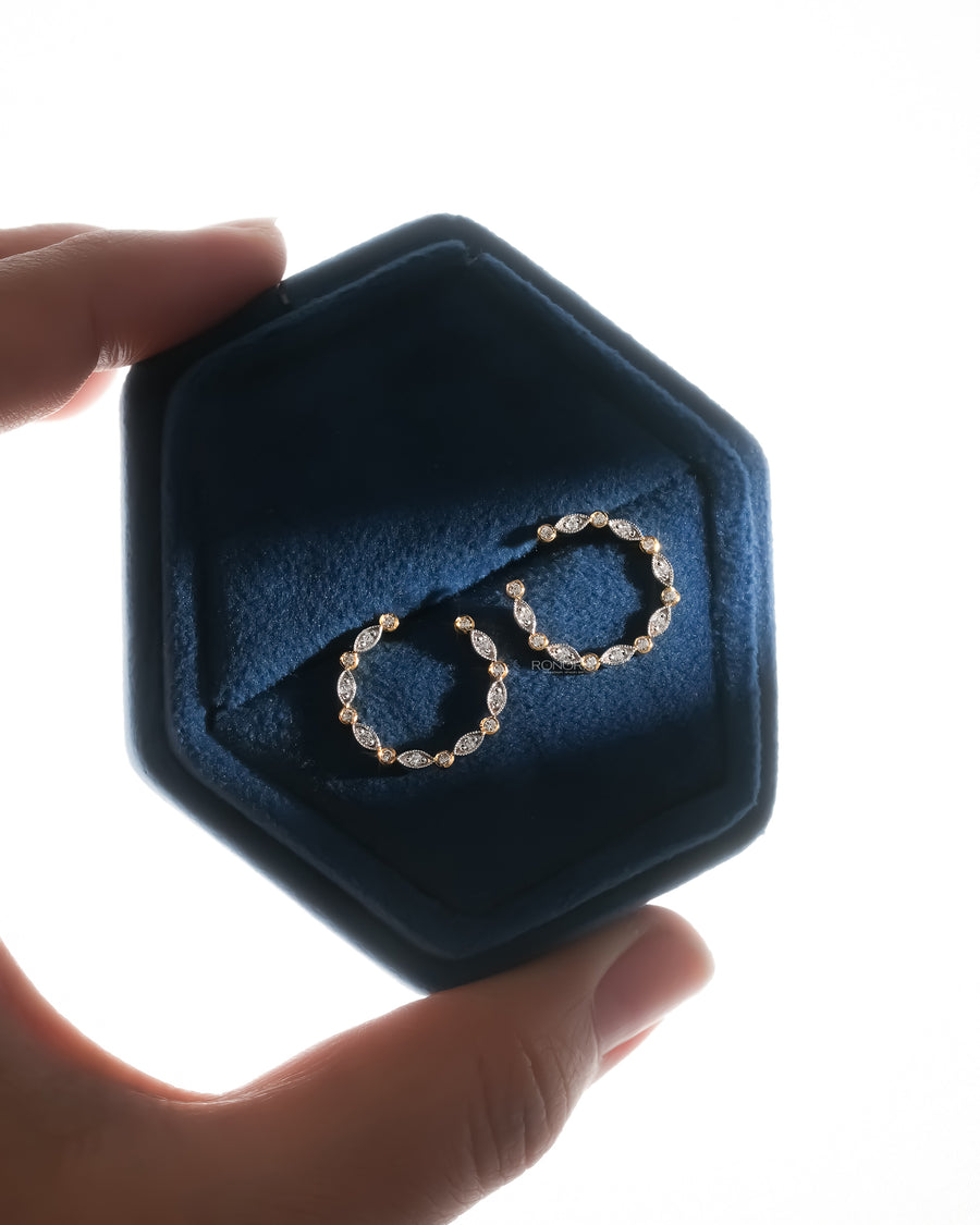 Open circle lab grown diamond earrings in a navy velvet hex box held between fingers, backlit