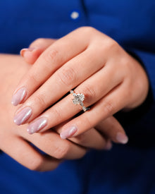 Oval lab grown diamond side-stone ring worn on hand in yellow gold