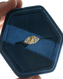 Fancy yellow lab grown diamond ring with two white side stones, top view in a blue velvet hexagon ring box