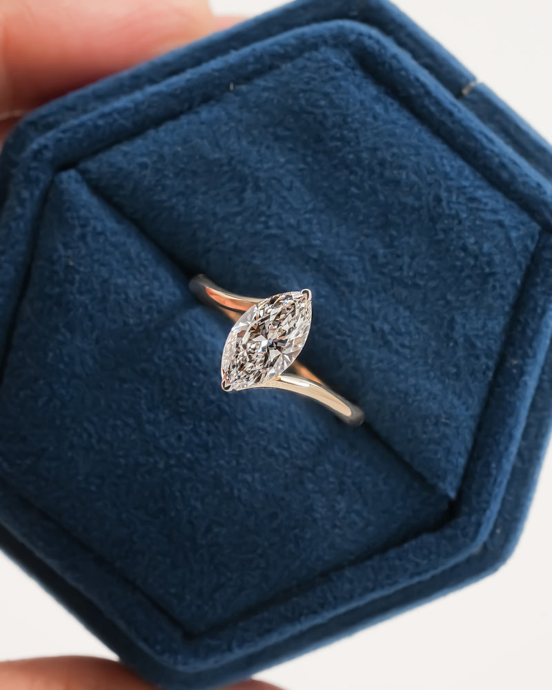 Marquise lab grown diamond bypass ring in a blue velvet hexagon jewelry box, rose gold band seen from above