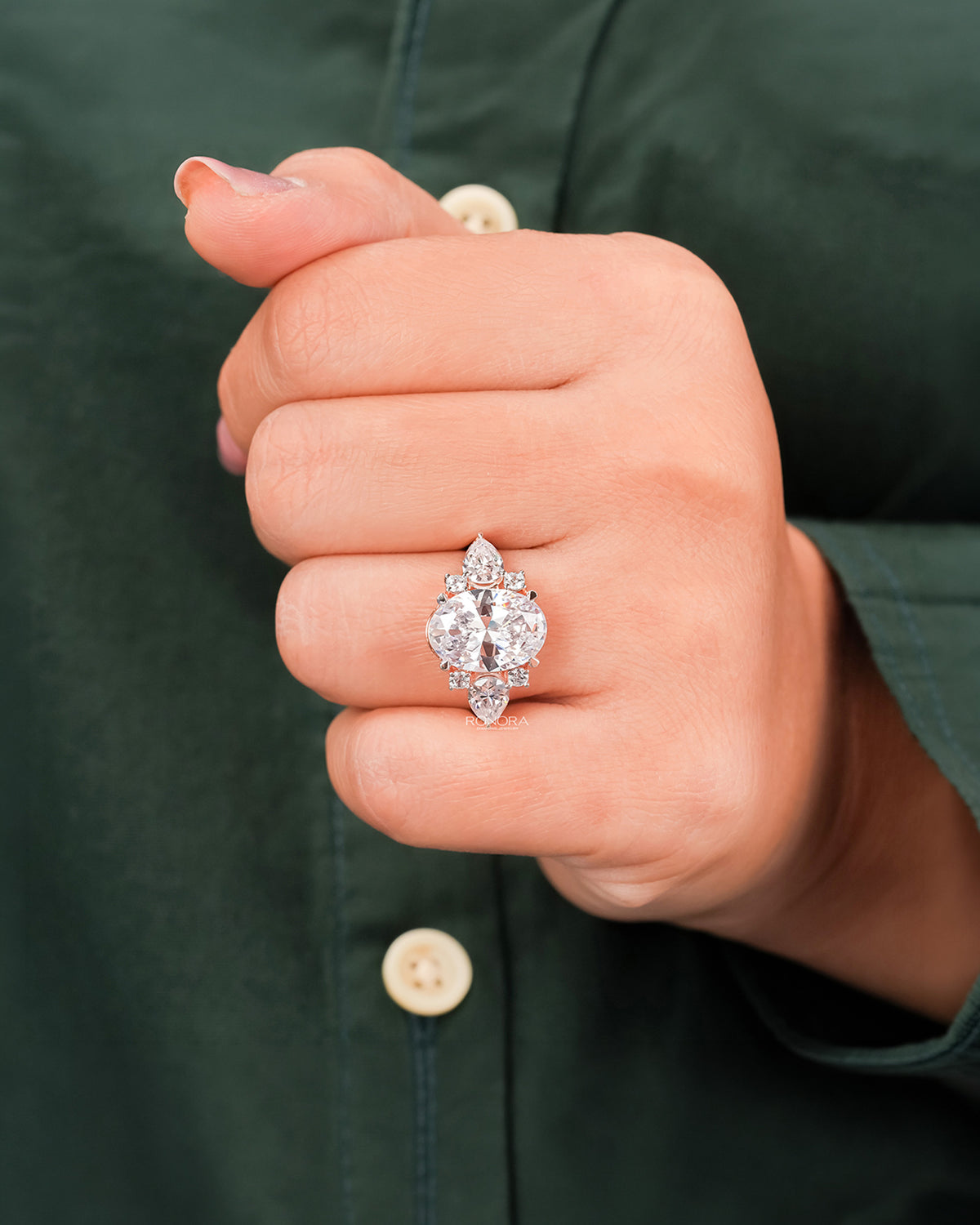 Oval moissanite three-stone ring worn on hand in rose gold