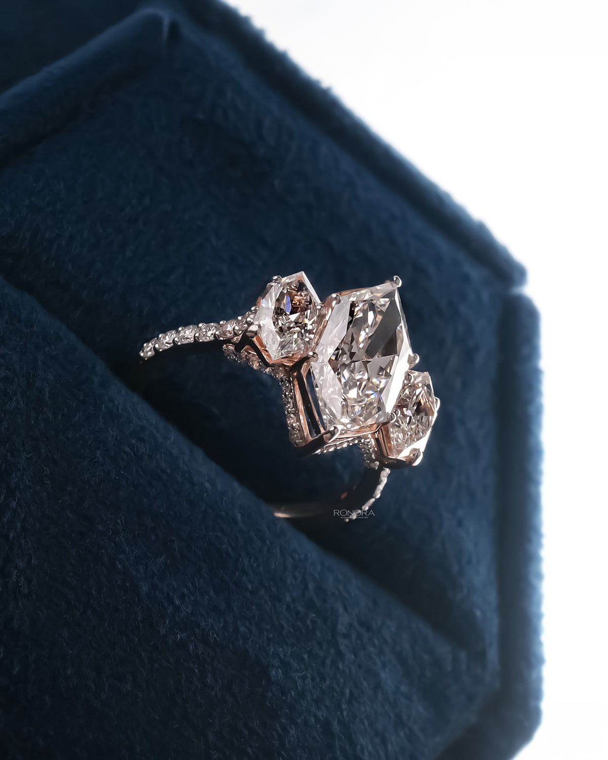 Angled view of marquise lab grown diamond three-stone ring with three-stone halo setting
