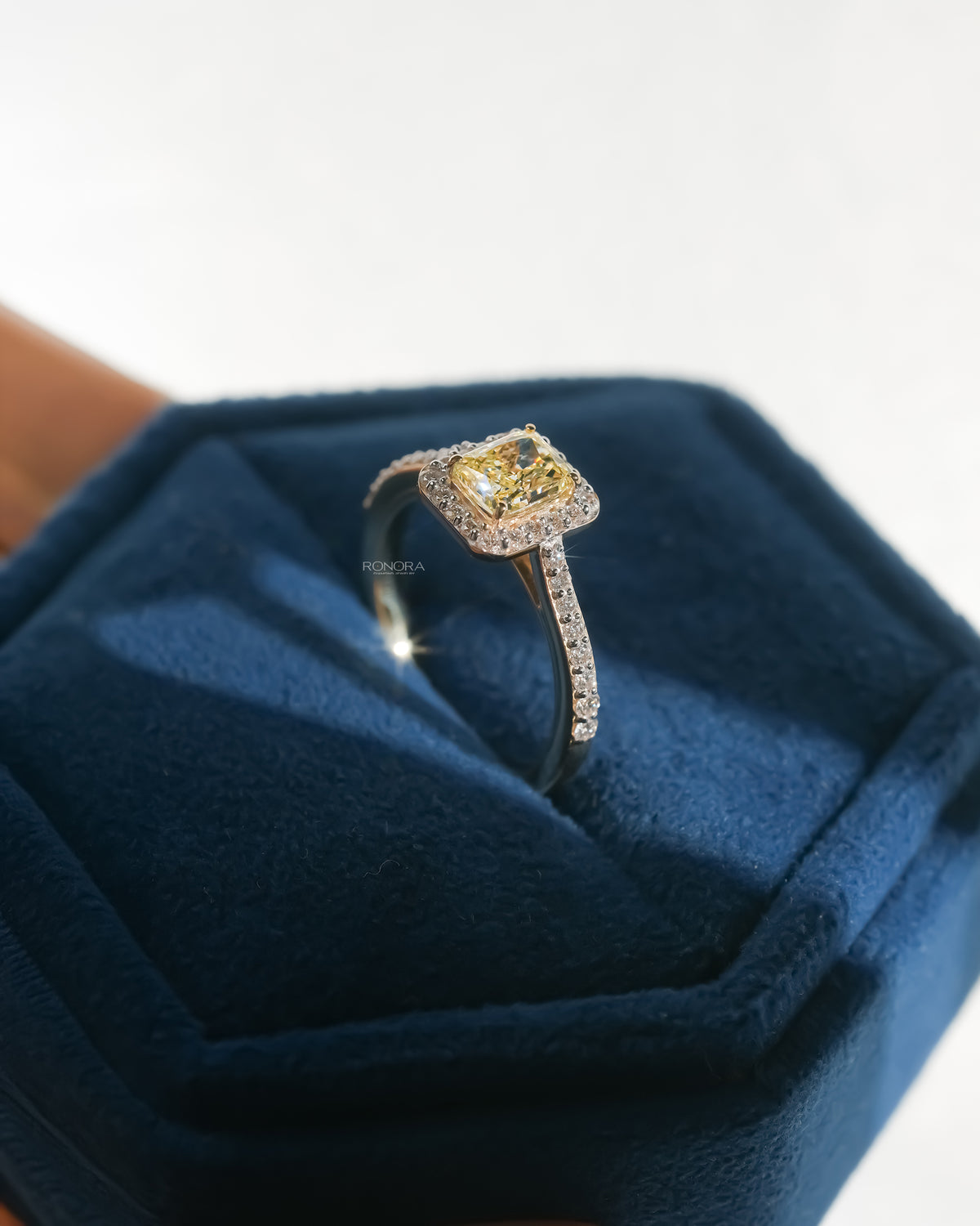 Fancy yellow lab grown diamond halo ring resting on blue velvet