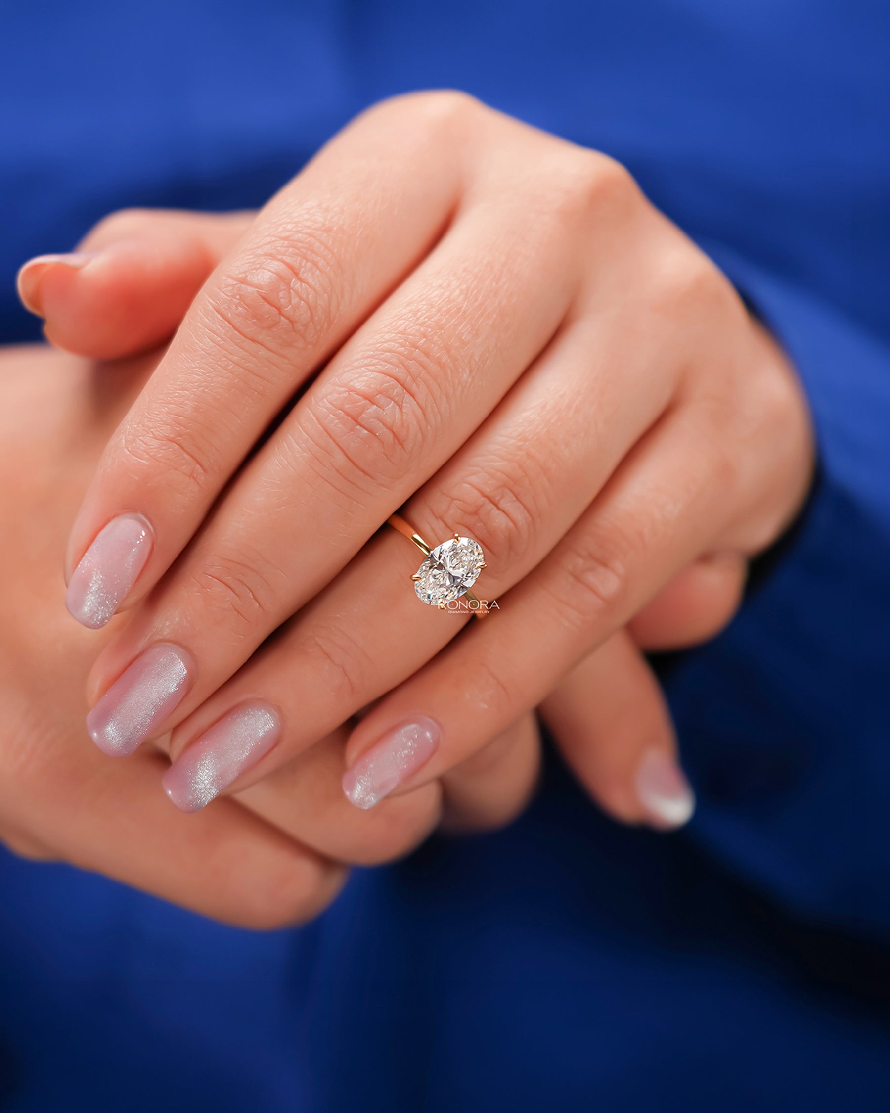 Oval lab grown diamond solitaire ring worn on hand in yellow gold