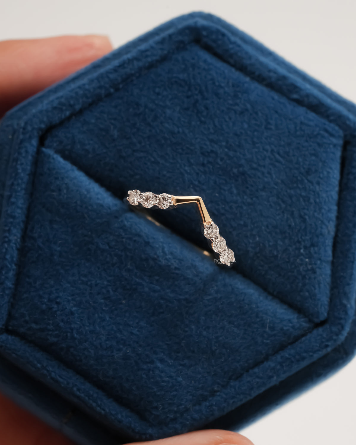 Chevron lab grown diamond wedding band in a blue velvet hexagon jewelry box, three round stones on each side