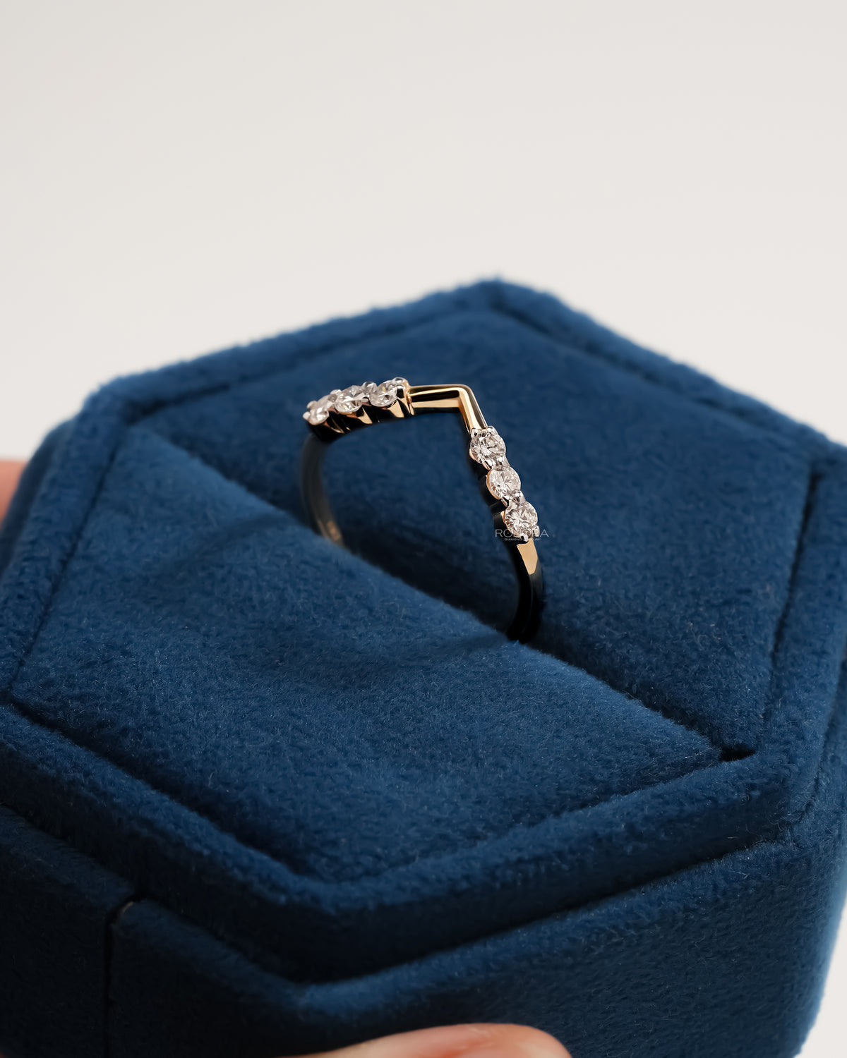 Chevron lab grown diamond wedding band standing in a blue velvet ring box, showing round stones and the V point