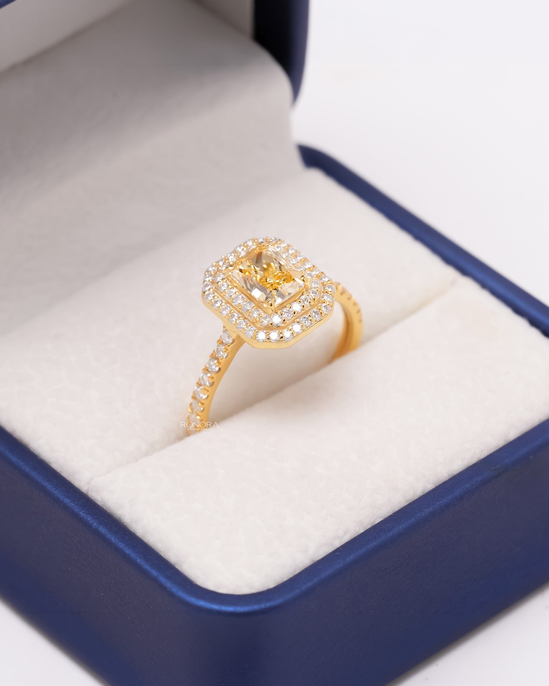 Angled view of yellow radiant lab grown diamond halo ring showing halo pavé setting