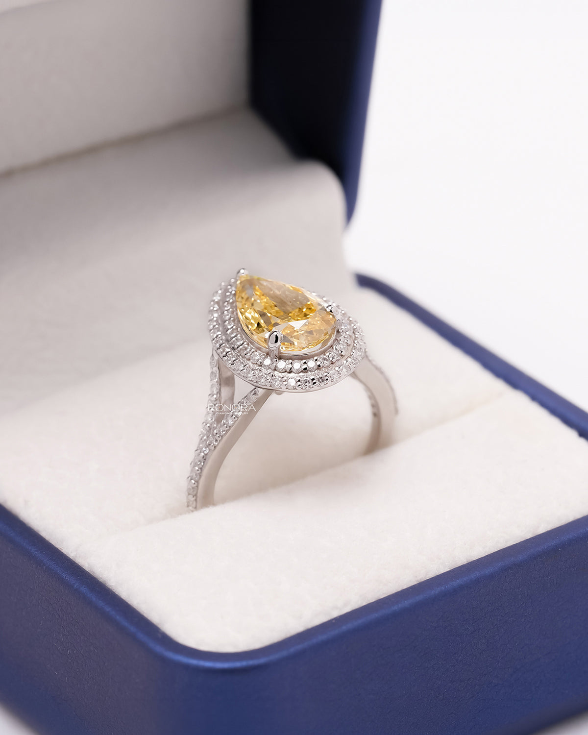 Angled view of yellow pear lab grown diamond halo ring showing halo split-shank setting