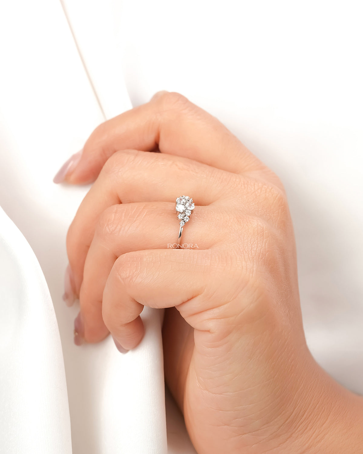 Floral lab grown diamond cluster ring worn with white silk