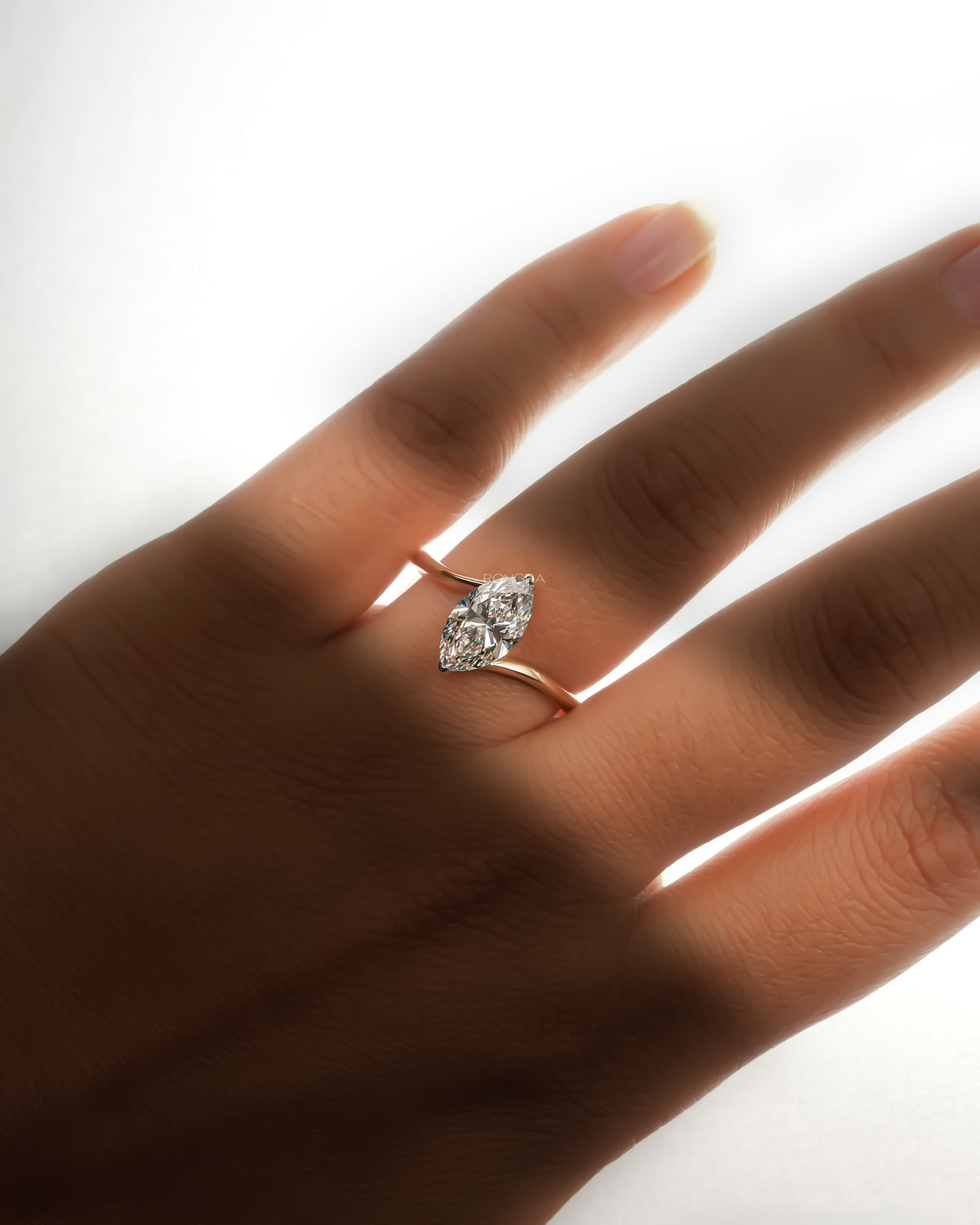 Marquise lab grown diamond bypass ring in rose gold worn on a hand in soft backlight