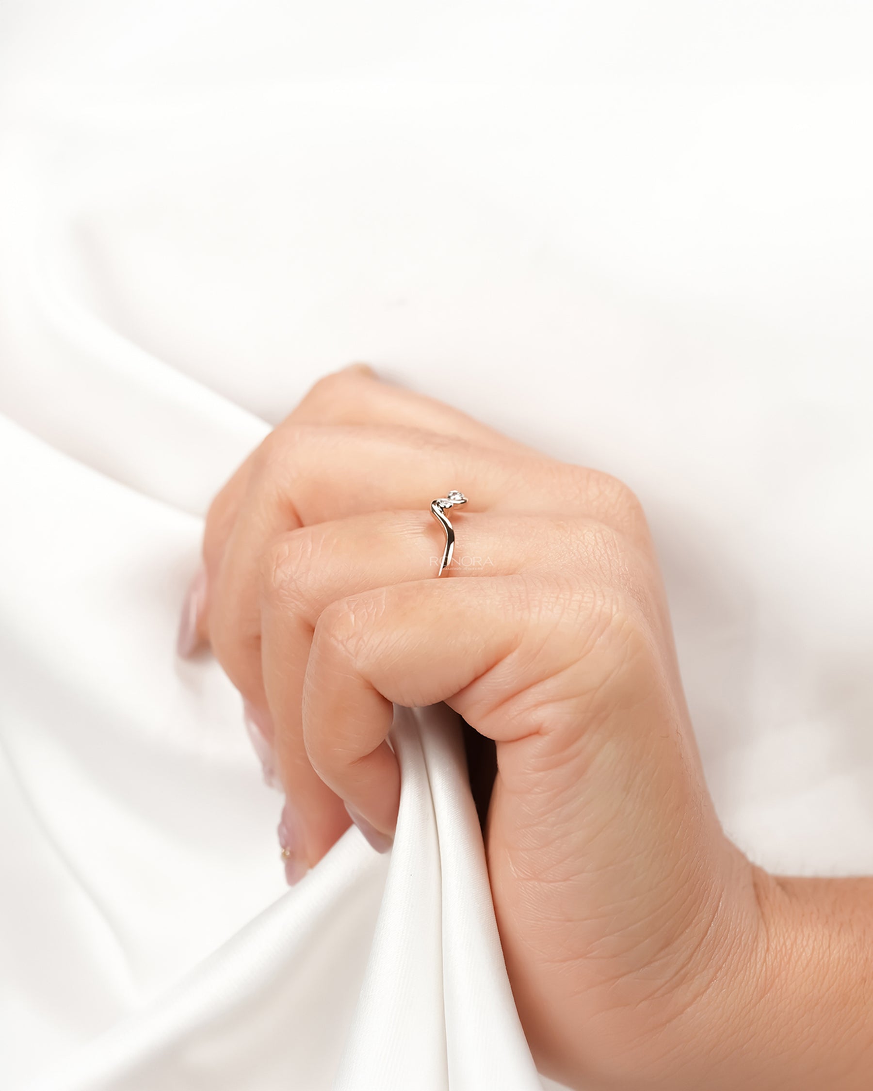 Side view of delicate lab grown diamond wave ring on hand showing slim curved band