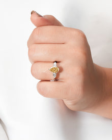 Yellow pear lab grown diamond three-stone ring worn on hand in white metal