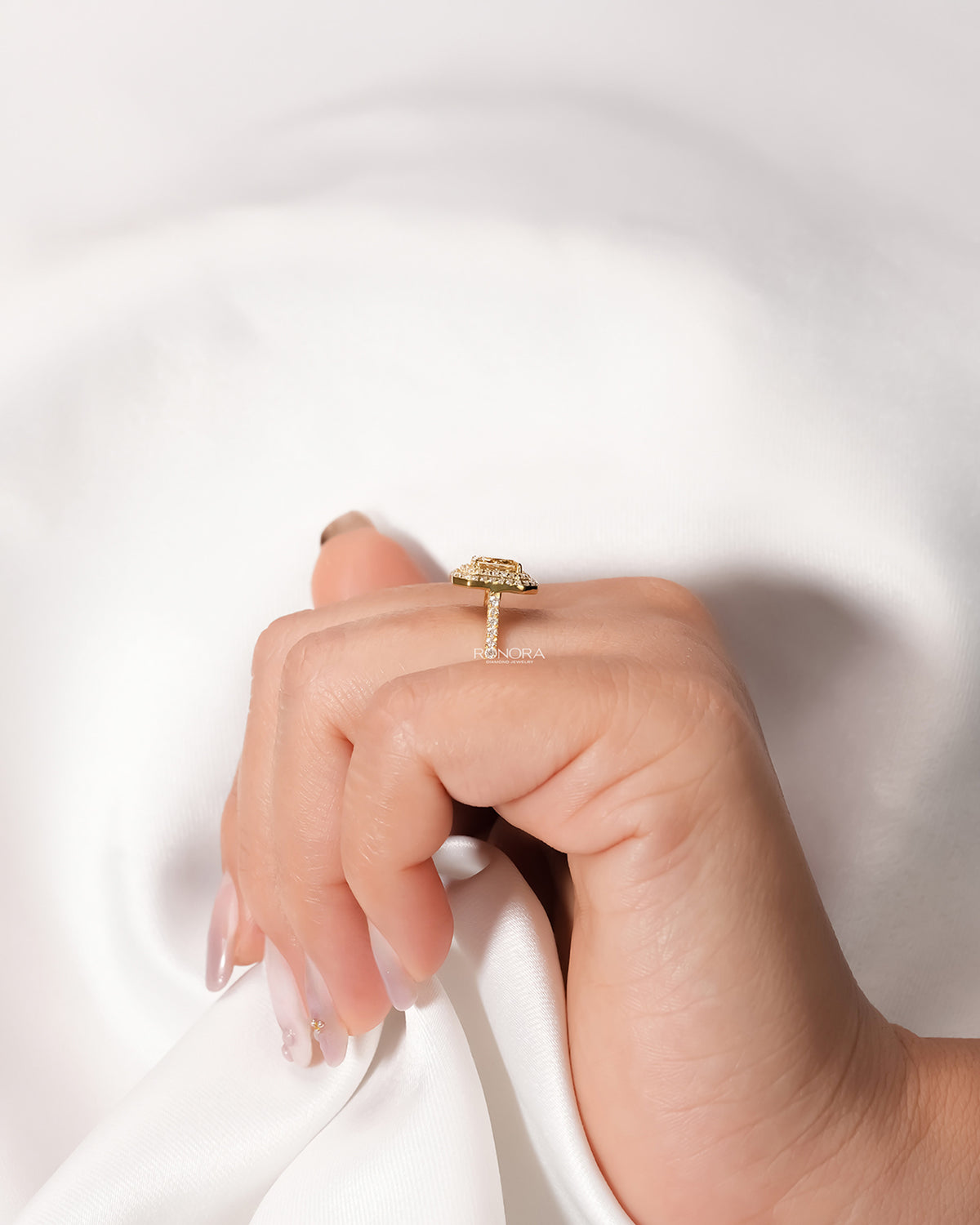 Yellow radiant lab grown diamond halo ring worn with white silk