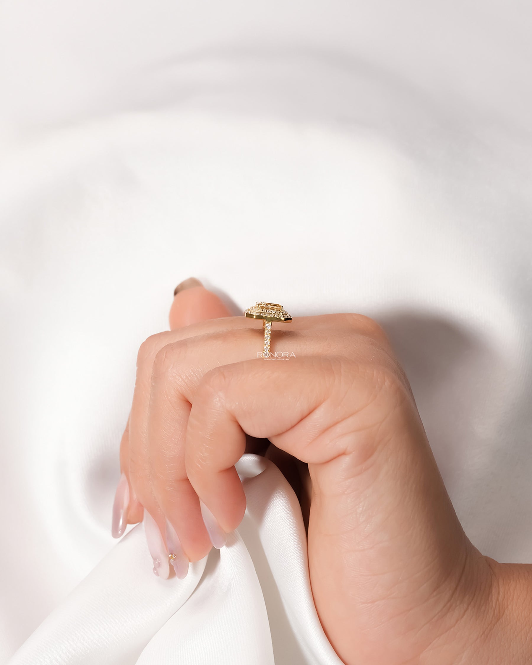 Yellow radiant lab grown diamond halo ring worn with white silk