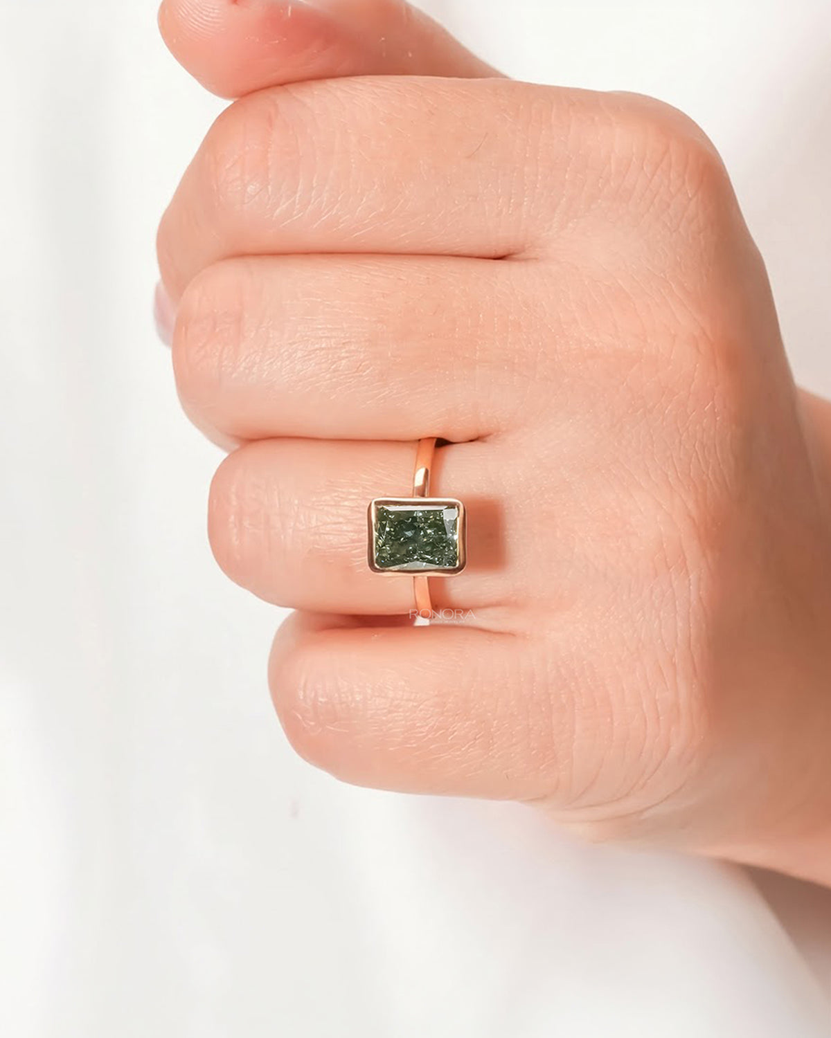 Green radiant lab grown diamond solitaire ring worn on hand in rose gold