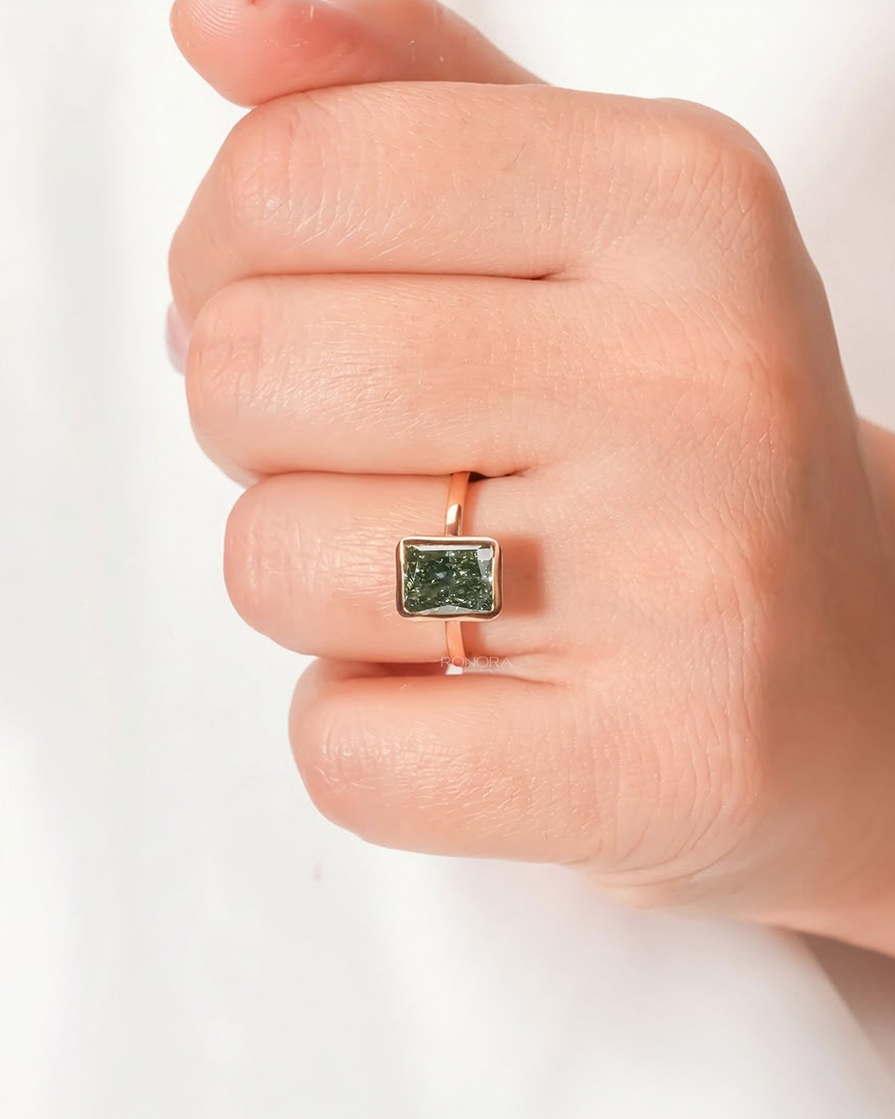 Green radiant lab grown diamond solitaire ring worn on hand in rose gold