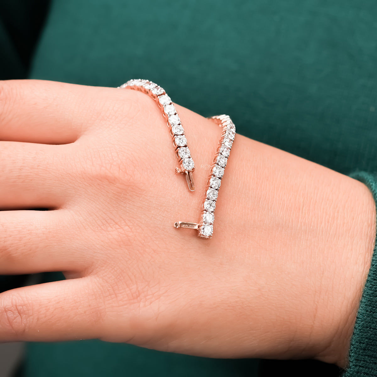 Round lab grown diamond tennis bracelet held above wrist