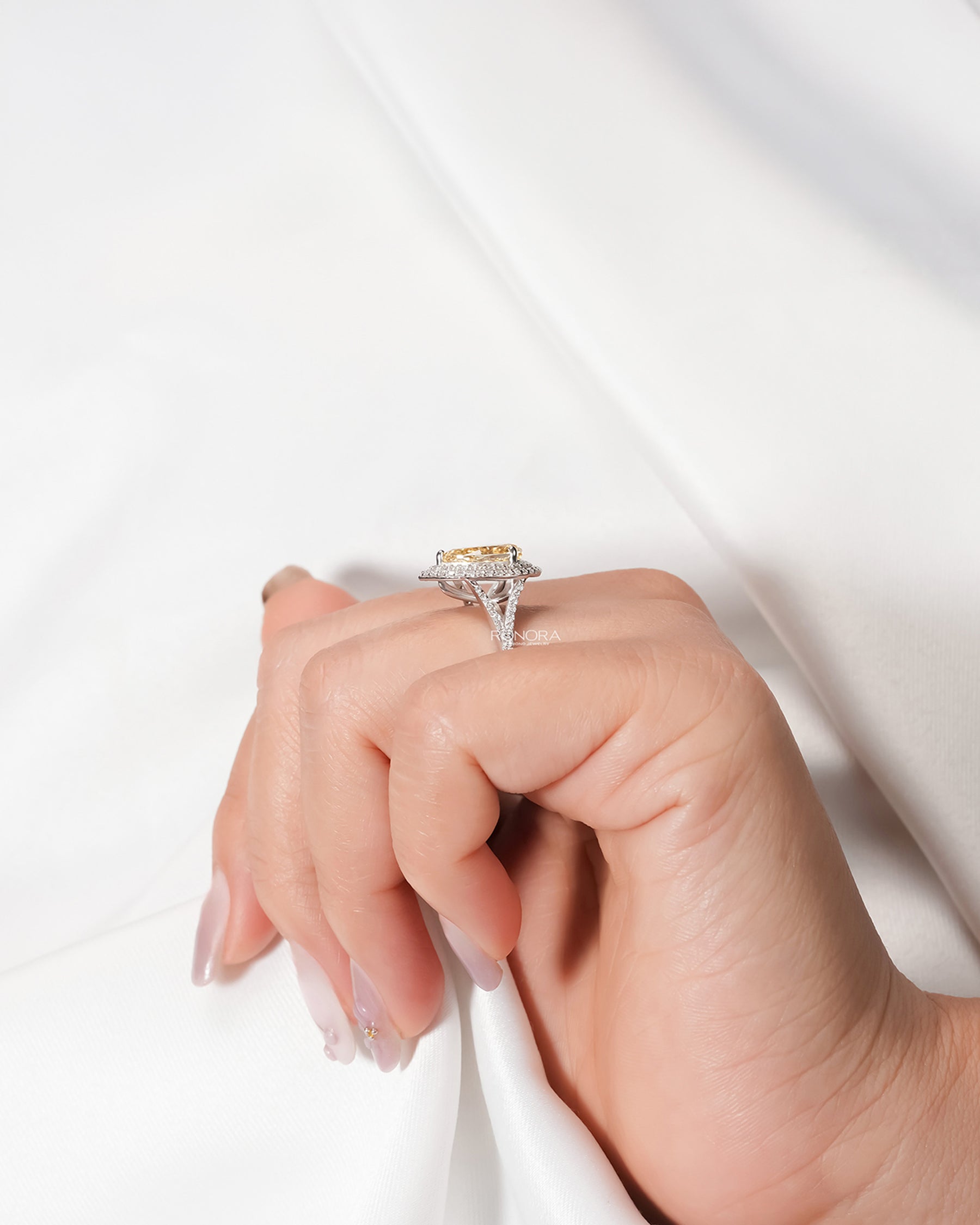Yellow pear lab grown diamond halo ring worn with white silk