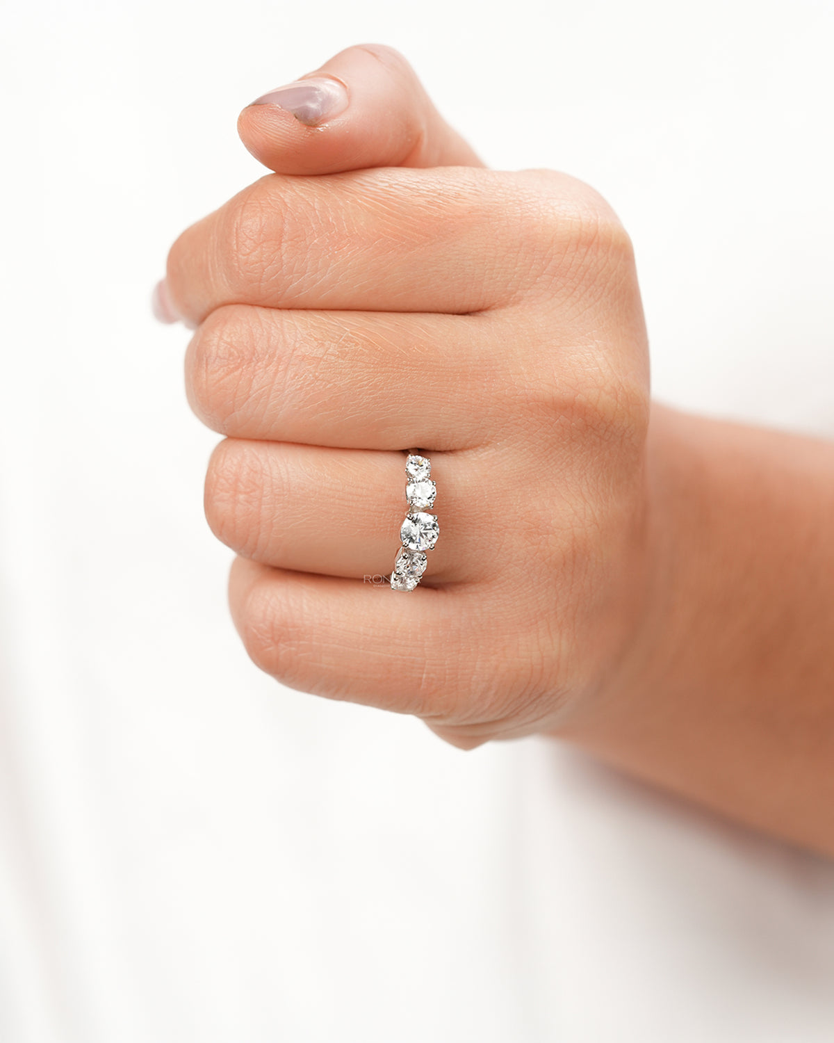 Round lab grown diamond five-stone ring worn on hand in white metal