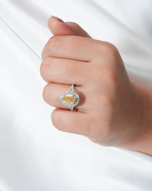Yellow pear lab grown diamond halo ring worn on hand in white metal