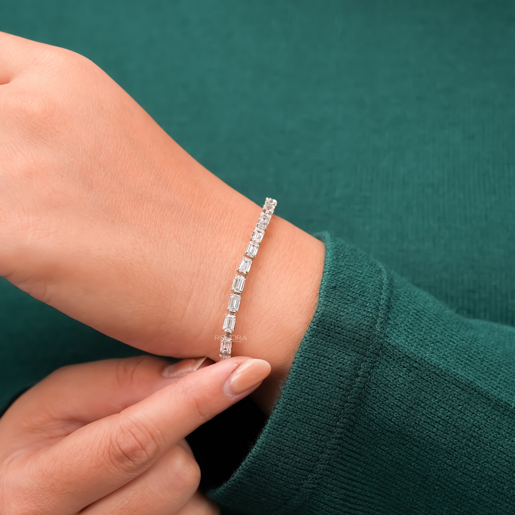 Emerald lab grown diamond tennis bracelet being adjusted on wrist