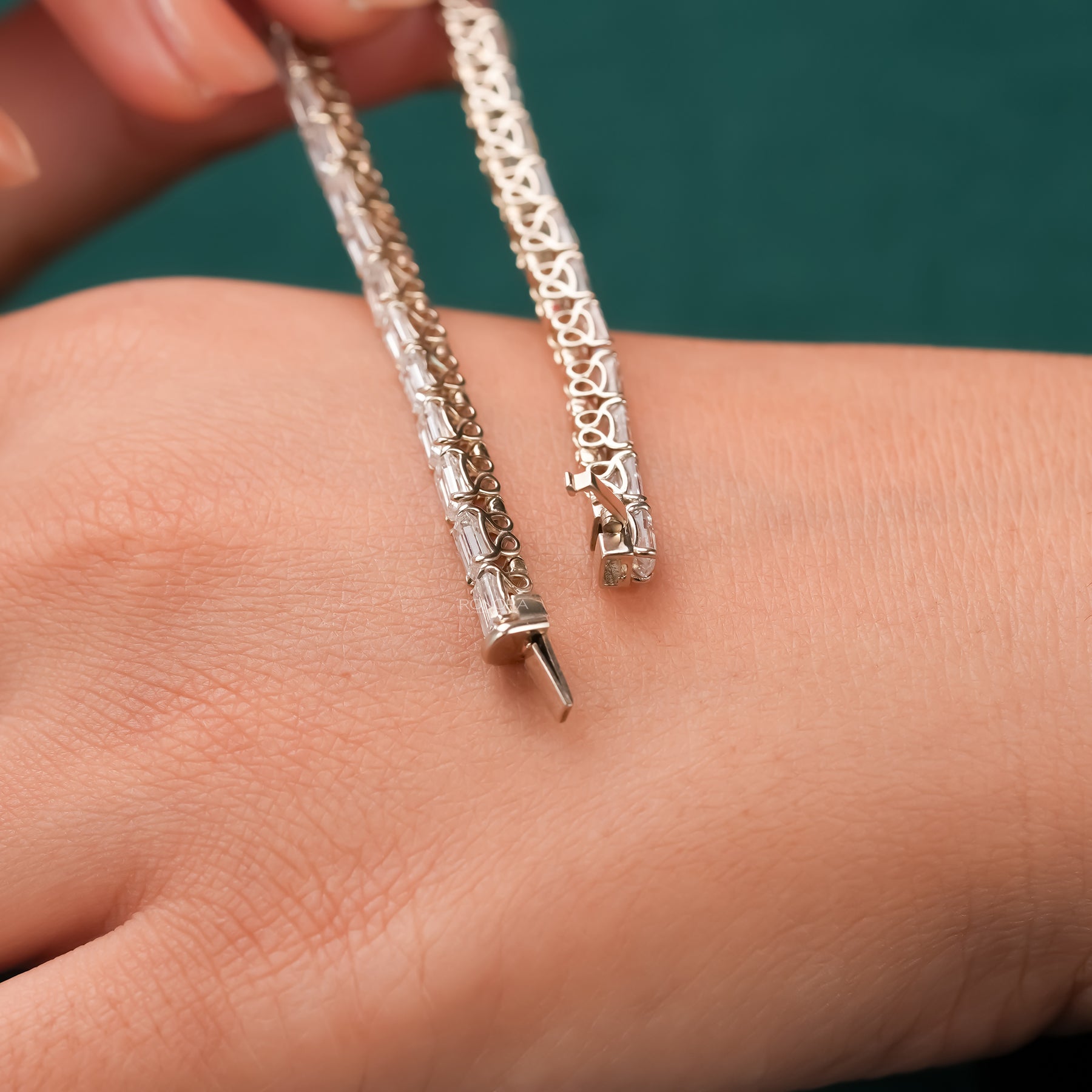 Emerald lab grown diamond tennis bracelet held above wrist